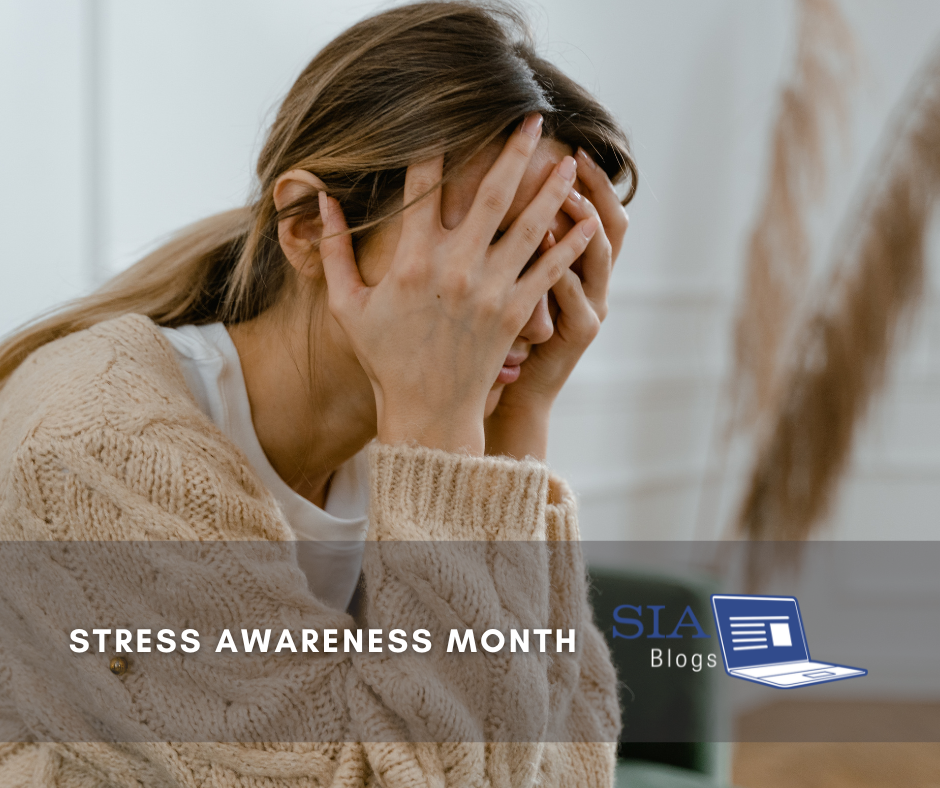 A woman sits with her hands covering her face, expressing distress or overwhelm. She appears to be struggling with stress, highlighting the theme of Stress Awareness Month.