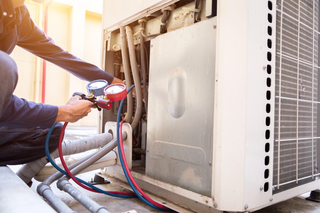 Technician performing HVAC maintenance in North Carolina on a commercial HVAC system to prevent equipment failures and property damage