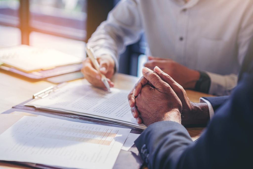 Business professionals reviewing a commercial contract to understand Certificate of Insurance vs Additional Insured requirements