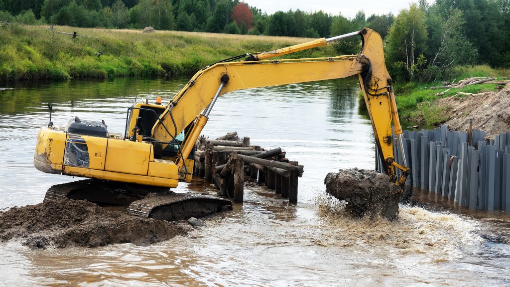 Excavation contractor in North Carolina using heavy equipment near a river, an example of runoff risk covered by pollution liability insurance for contractors.