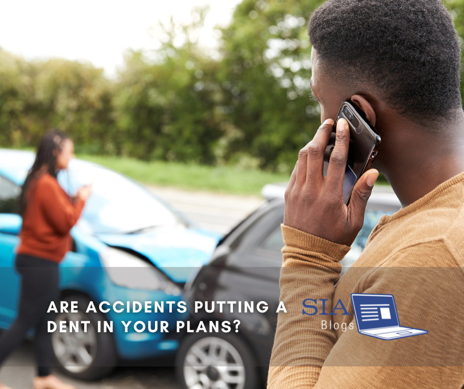 A man is speaking on the phone while standing next to a car involved in a minor accident, with visible damage on the front of the blue vehicle. In the background, a woman appears to be taking a photo of the scene with her phone. The caption reads, "Are Accidents Putting a Dent in Your Plans?" with the SIA Blogs logo.