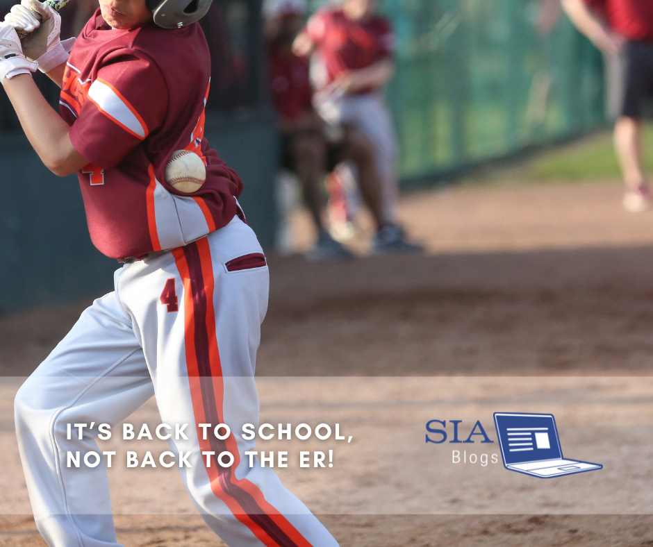 A young baseball player in a red jersey and gray pants is in the middle of swinging at a pitch on a baseball field. In the background, several teammates are seated and watching the game. The caption reads, "It’s Back to School, Not Back to the ER!" with the SIA Blogs logo.