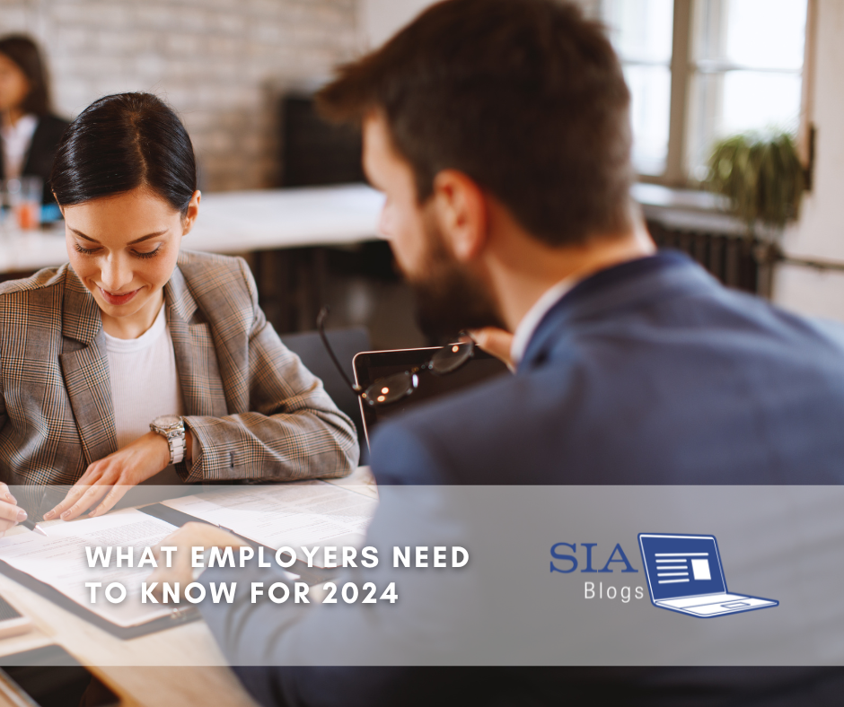 A woman in a plaid blazer reviews documents at a table while a man in a suit sits across from her, holding his glasses. The caption reads, "What Employers Need to Know for 2024," along with the SIA Blogs logo.