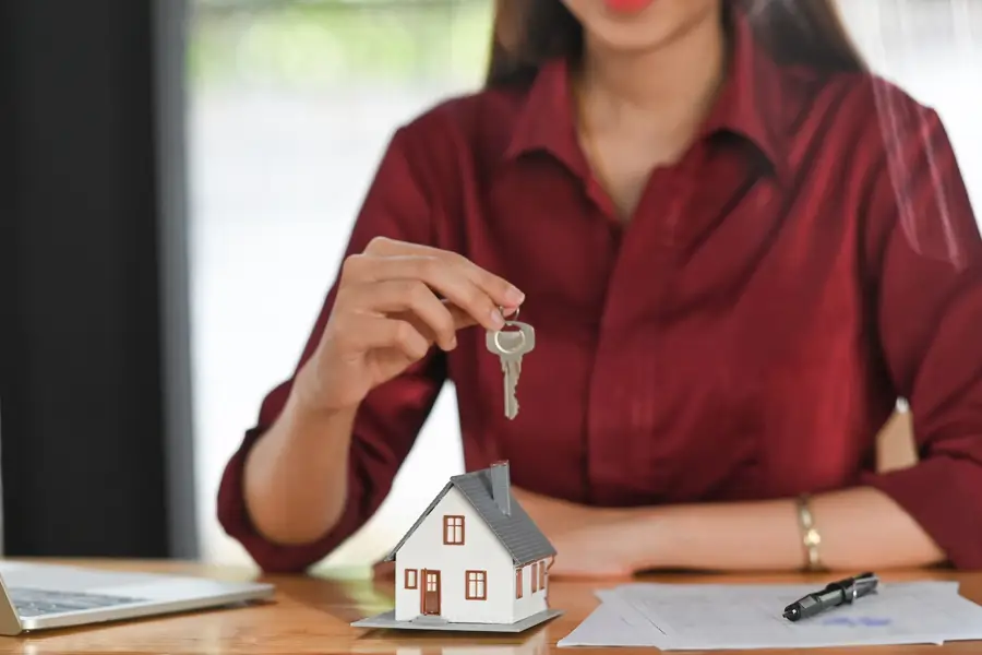 Woman holding key over model house